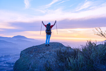 young man on the mountain with open arms celebrating his climb