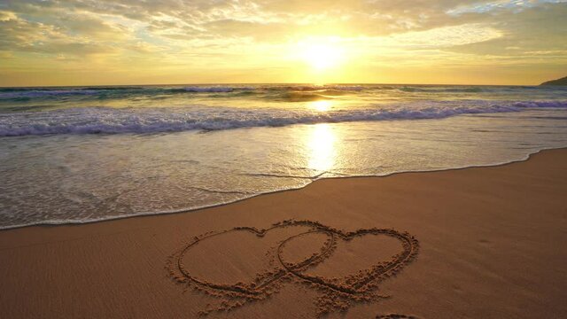 Beautiful hearts symbol on beach sand over sunset Valentines day on the beach Gift celebration romantic light sunset A heart is drawn on the seashore The inscription on the beach sand