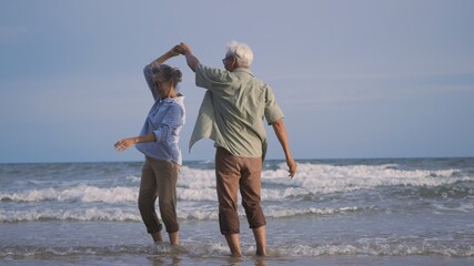 Happy Asian senior man and woman couple smile dancing resting relax on the beach honeymoon family...