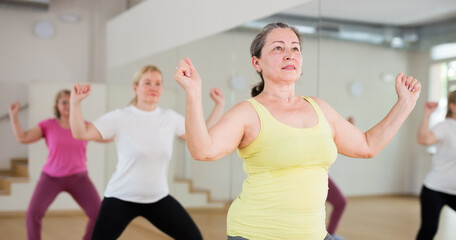 Group of adult women warming up before dance training in fitness center