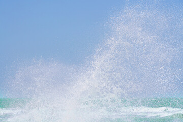 splashing water of sea wave crashing on shore spraying white water foam in air