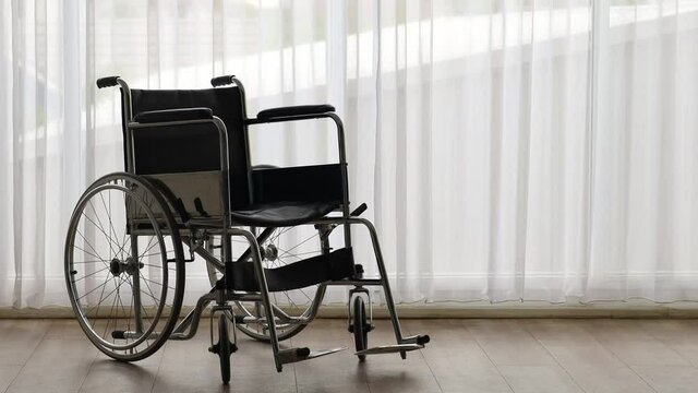 Zoom out technic video, wheelchair with nobody in the room with a white curtain in the background. Disable people and health care concept.