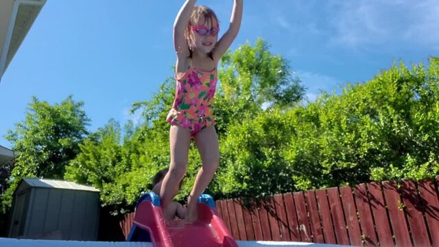 Little girl jumping into a kiddie pool in slow motion.