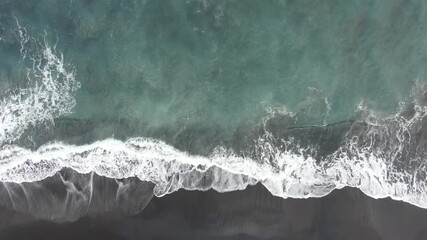 wave breaking on the shore on the black sand beach drone footage