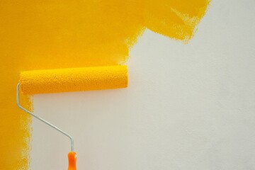Paint yellow with a roller on the wall DIY by yourself