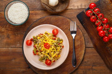 Risotto with mushrooms and cheese on a wooden background near rice and vegetables.
