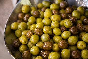 Different marinated olives on a silver bowl.