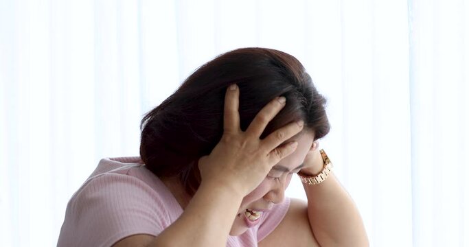 A senior woman suffered and pain from headaches using hand holding head. Concept of older person health care.