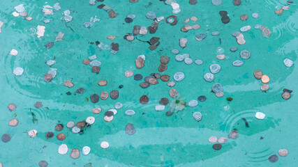Wishing well pond coin fountain filled with money and spare change reflecting in rippling water...