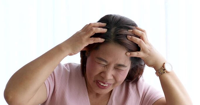 A senior woman suffered and pain from headaches using hand holding head. Concept of older person health care.