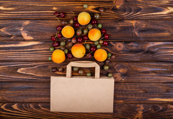 Health food fruit in supermarket grocery shopping concept. Zero waste shopping. Shopping groceries online. Fruits in paper bag on wooden background flat lay. Many different fruits falling out of bag