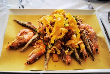 Crispy and hot mixed fried fish dish just served at a restaurant table