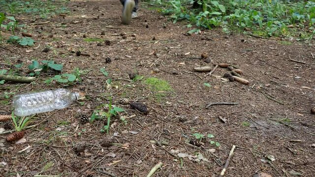 Man walks in the forest and dumps a plastic bottle