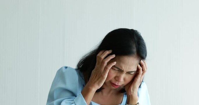A senior Asian woman suffered and pain from headaches using hand holding head. Concept of older person health care.