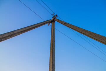 Triple pole of power lines against the sky.