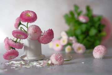 Pink daisies in a white ceramic stack with green leaves nearby.