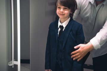 Smiling boy and his father trying school uniform for future schooler. 