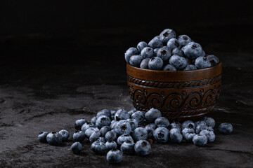 Fresh juicy blueberries in the bowl on the black background. Low key photography