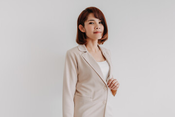 Confident Asian working woman in beige blazer isolated on white background.