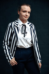 Vertical photo an adult woman with a smile stands straight, looking into the camera, on a black background.