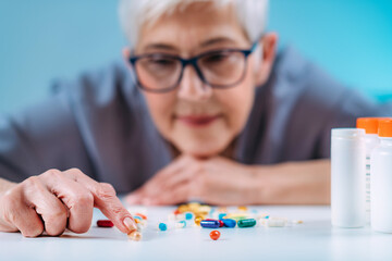 Senior patient counting pills. Medicine non-adherence.