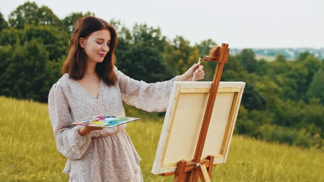 Young woman drawing a painting on nature - measuring the proportions