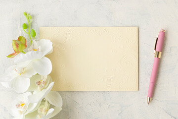 Congratulations or holiday concept. flat lay of blank textured leaf with pink pen and white orchid on white concrete background.