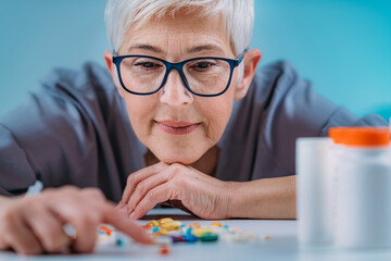 Prescribed medication non-adherence. Senior female patient counting pills.