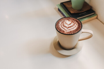 Hot latte coffee served in white mug on the table in warm morning.