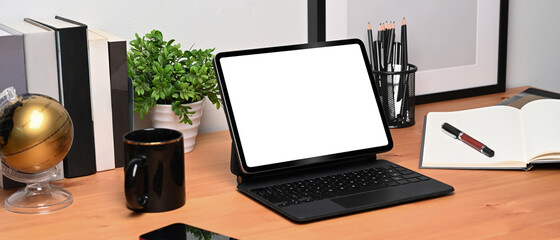 Mock up computer tablet, notebook, houseplant and coffee cup on wooden desk.
