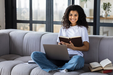Learning online concept. Portrait young African American woman student study at home using laptop, smiling, looking at the camera. Distance education at home