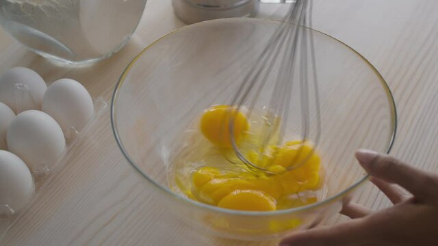 Traditional breakfast recipe. Black woman whisking eggs in glass bowl at kitchen, cooking scrambled egs for family, slow motion