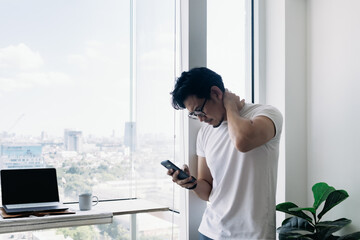 Serious Asian man working with computer and phone with high rise view.
