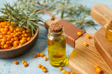 Bottle of sea buckthorn essential oil on color background