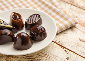 Plate with sweet chocolate candies on table