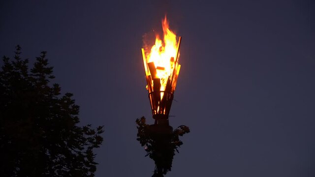 Midsummer A Latvian man with an oak leaf wreath lighting up a pūdele (a container filled with tar, decorated with oak leaves and attached atop of a pole)