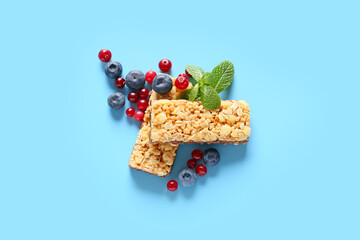 Healthy cereal bars and berries on color background