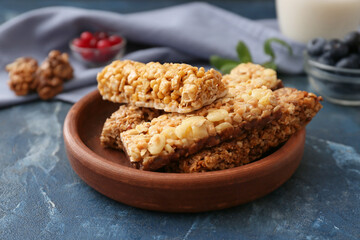 Plate with healthy cereal bars, berries and nuts on color background