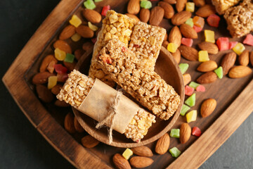 Plate with healthy cereal bars, candied fruits and nuts on dark background