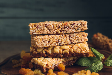 Board with healthy cereal bars and raisins on wooden background