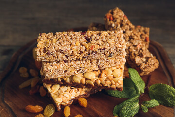 Board with healthy cereal bars and raisins on wooden background