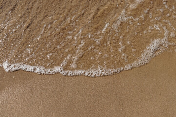 Tidal waves with ripples and foam on sea coast