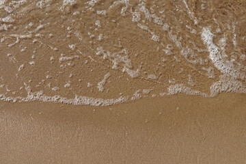 Low tidal waves with ripples and foam on sea coast
