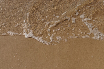Fototapeta na wymiar Low tidal waves with ripples and foam on sea coast