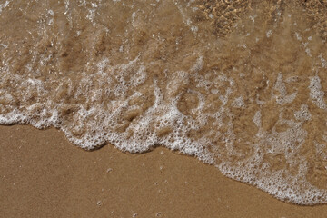 Tidal waves with ripples and foam on sea coast
