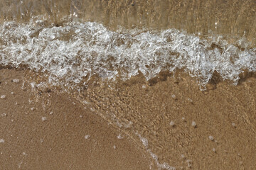 Tidal waves with ripples and foam on sea coast