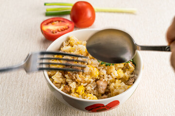 Man hand using metal spoon and fork scoop delicious thai style homemade pork and egg fried rice.