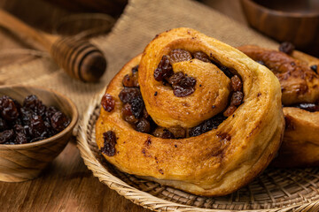 High angle closeup view of delicious homemade raisin cinnamon cake roll in bamboo tray.