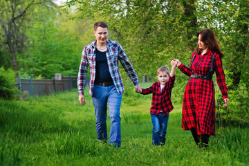 Happy family outdoors spending time together. Father, mother and son are having fun on a green grass in the park. International family day concept