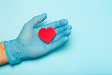 Fototapeta premium Heart in the hands of a doctor on a colored banner background. Donation, charity, health treatment, help concept. Medical health background and love. 